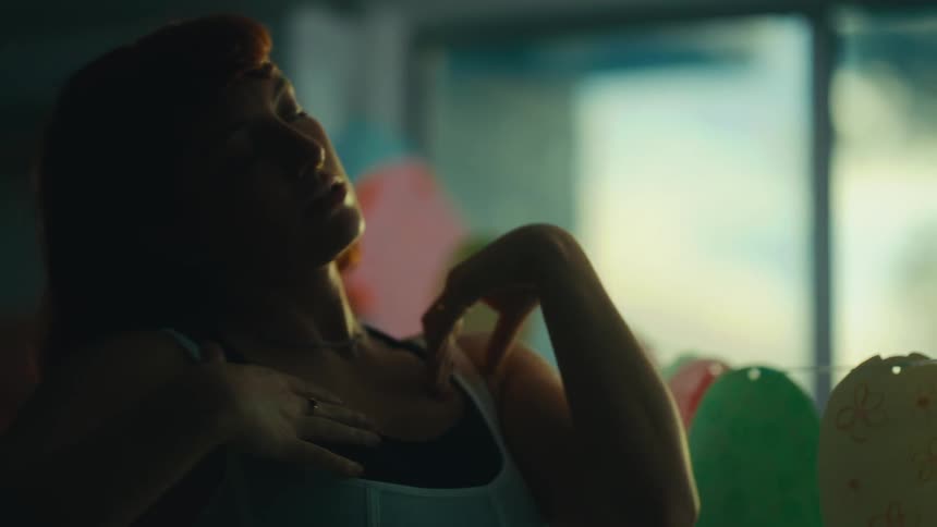 Redheaded woman dances near a line holding small flat oval pieces