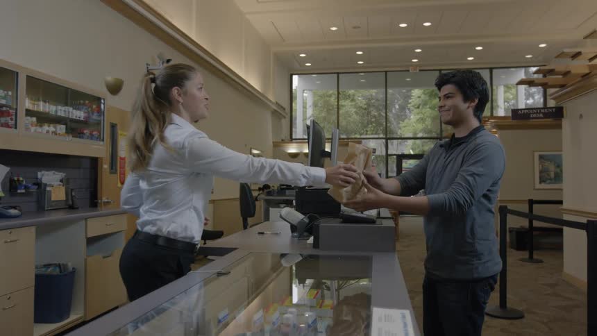Woman placing a purchased item in a bag and handing it to the customer in a shop