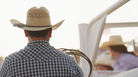 Man from behind with cowboy hat holding a rope