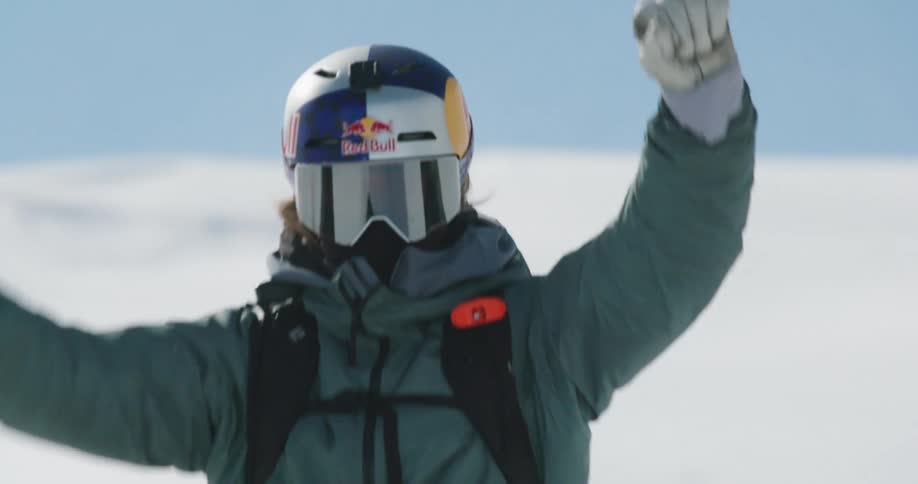 Person riding a snowmobile and cheering with arms raised
