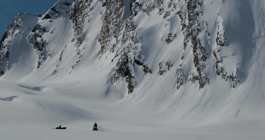 Snowy mountain landscape and a person riding a snowmobile
