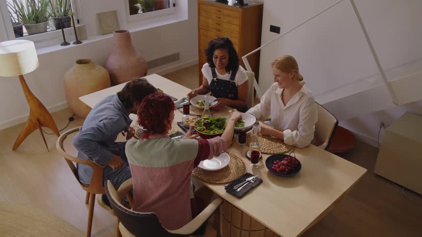 Friends talk and smile at a get together while their host serves them