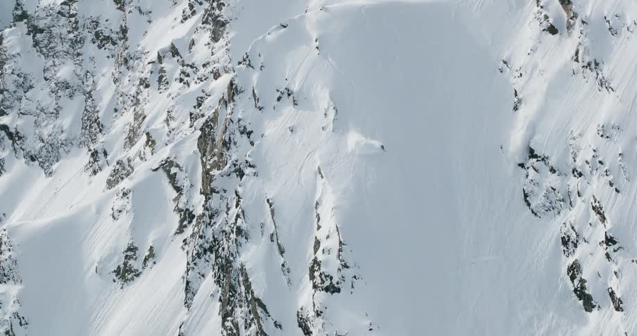 A high angle static shot of a snowy mountainside showing a clear ski run