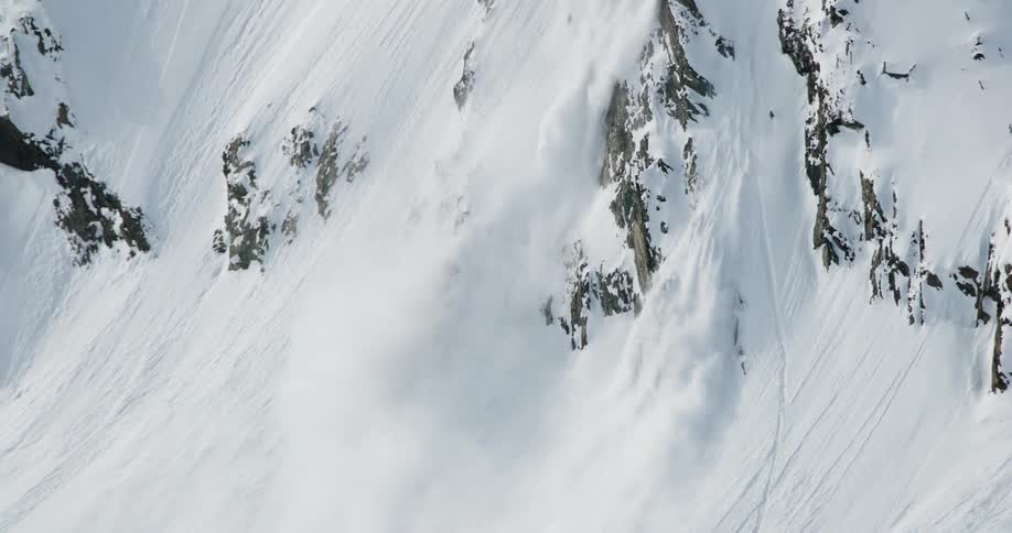 An avalanche of snow slides down a steep mountain