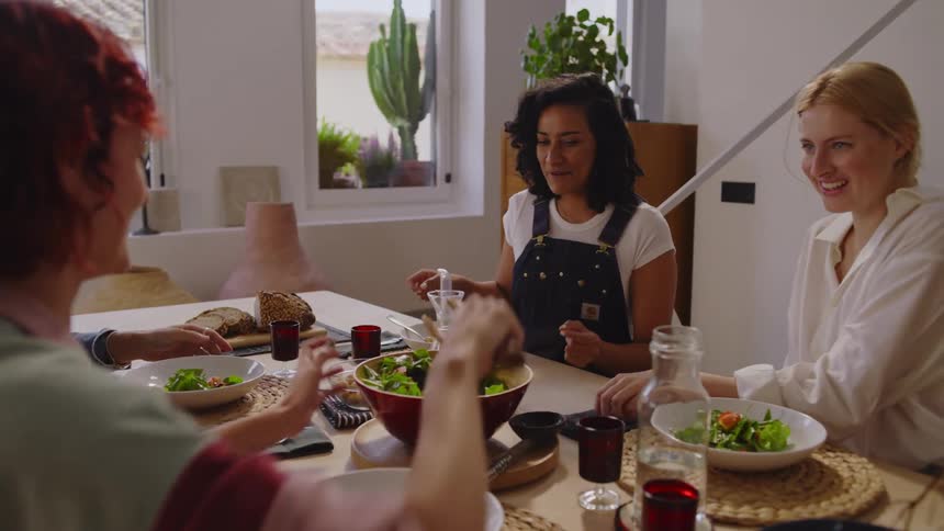 Friends laugh while eating brunch together at one of their homes