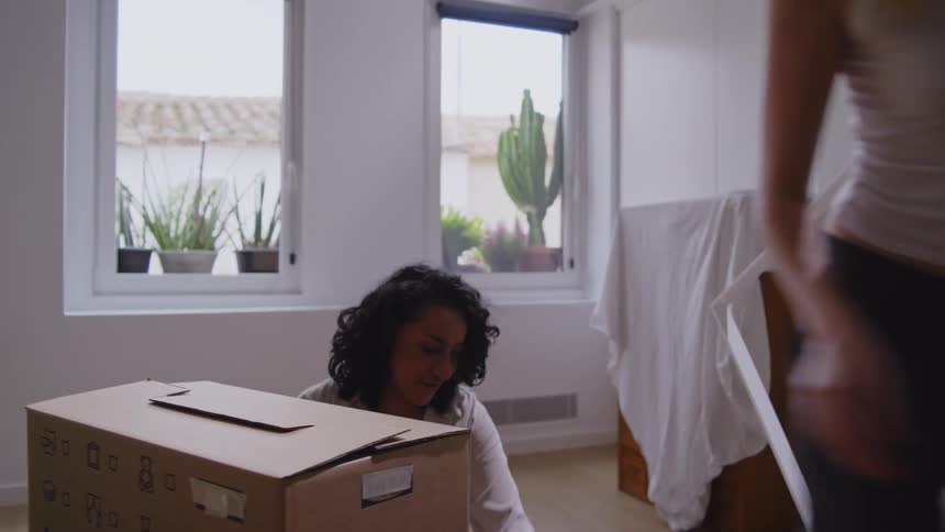Two women in a living room full of moving boxes