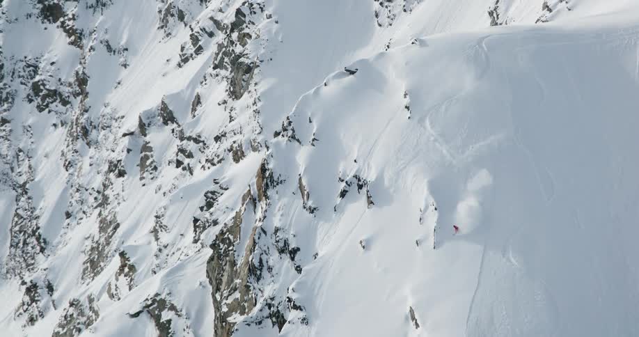 Skier skis down a steep snow covered mountain slope leaving tracks