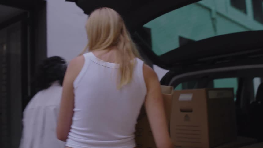 Two women unpack boxes and carry them inside