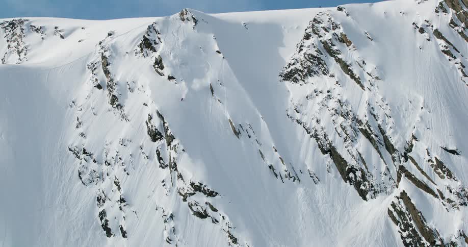A person skis down a steep snowcovered mountain