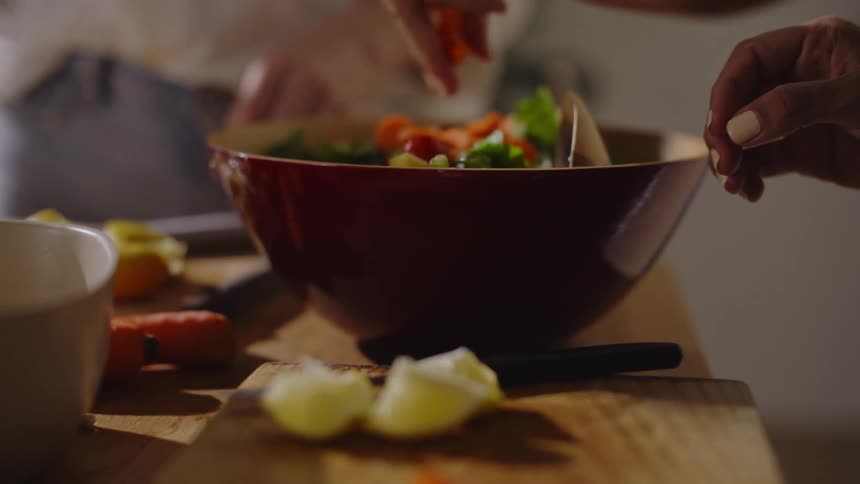 Two people preparing a salad with chopped vegetables
