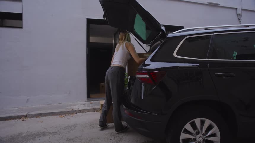 Women unload boxes and plants from a car