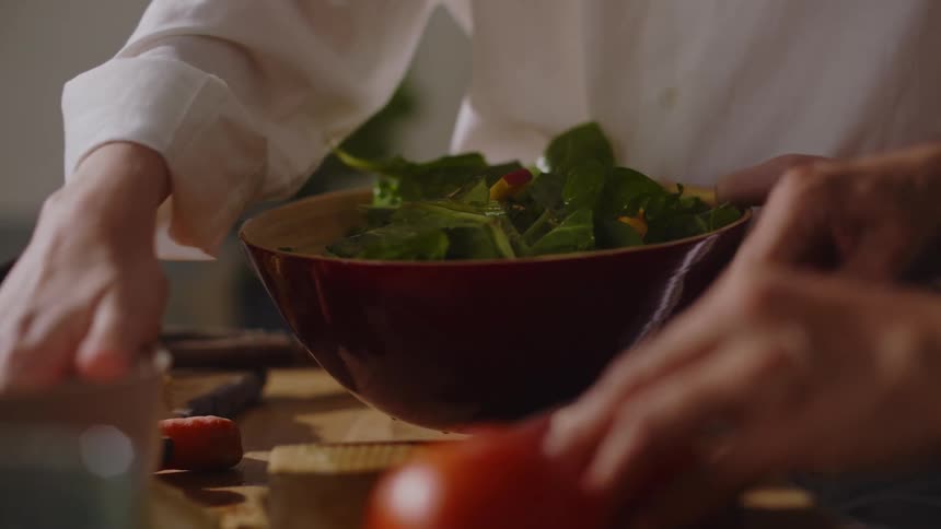 A woman puts salad in the bowl