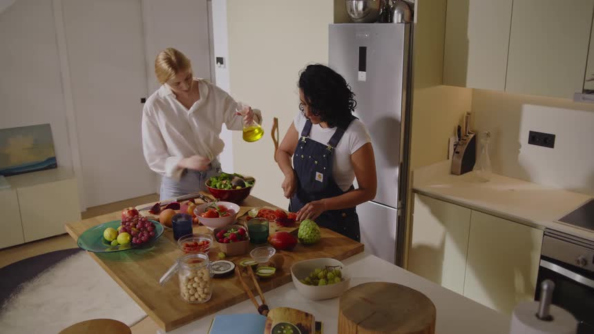 Two women in the kitchen preparing salad and fruits