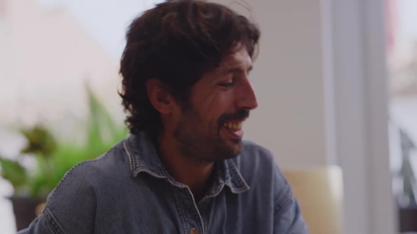 A group of friends are sitting indoors while laughing and talking together