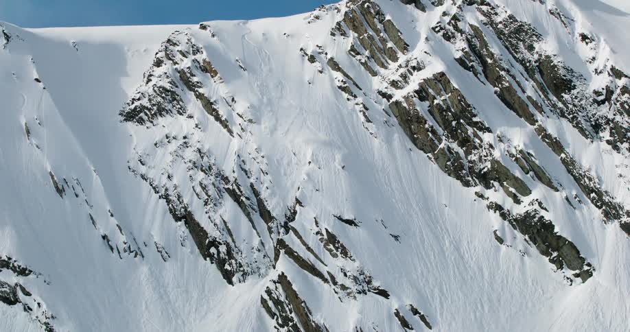 A person causes a small avalanche as they ski down the mountain