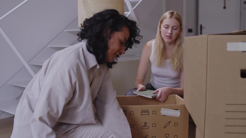 Two women are unpacking books from boxes