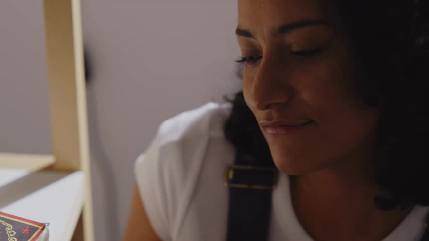 The face of a young woman who is talking to someone in front of her and she has a subtle smile on her face