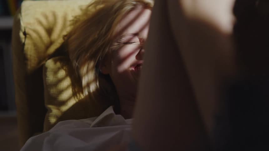 A woman is laughing and kicking her legs on the couch