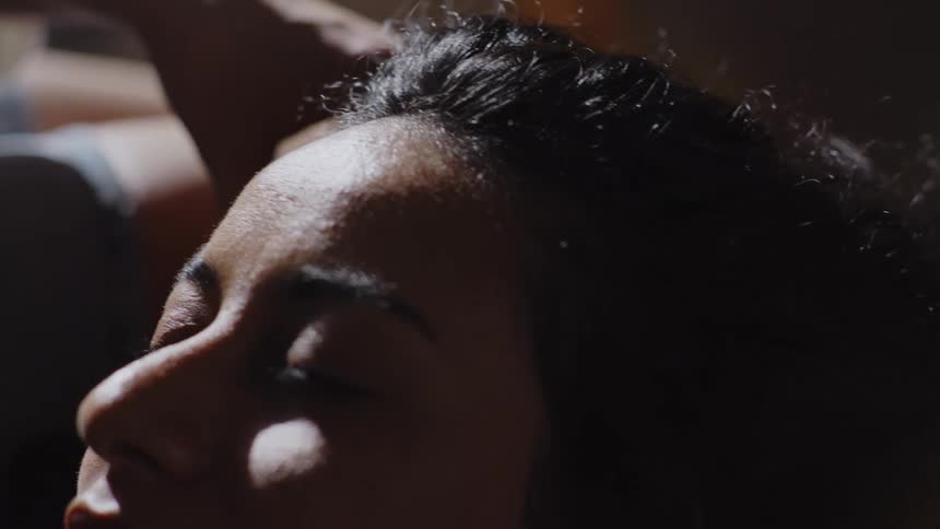 A woman gently caresses her partners face as they relax together on a cozy couch at home