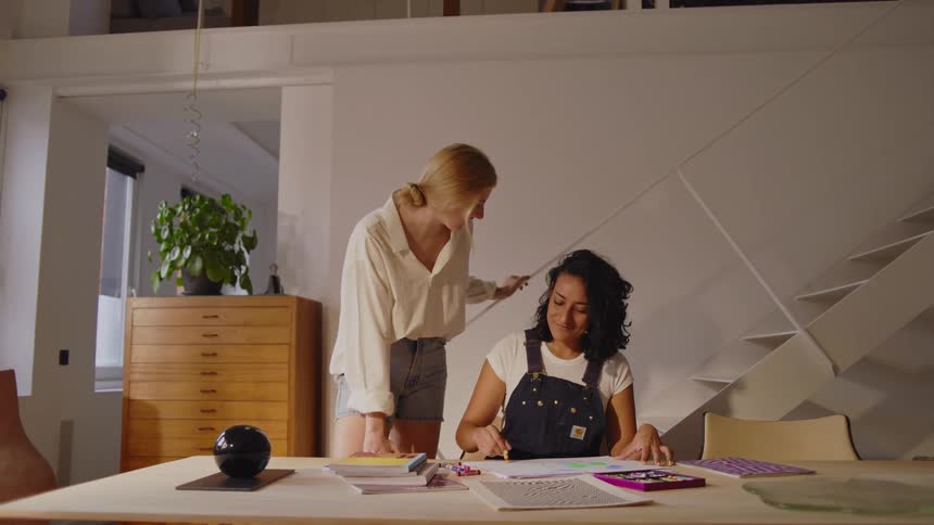 Woman discusses with an artist drawing at a table