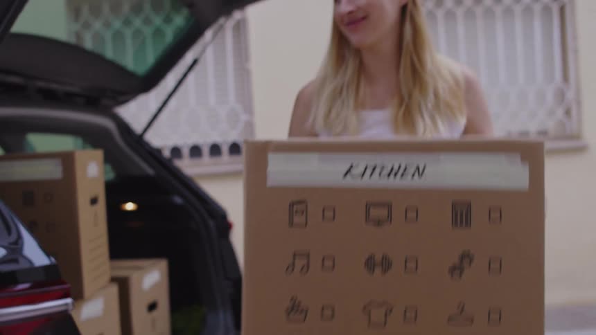 Woman opening the trunk of her car and taking out moving boxes
