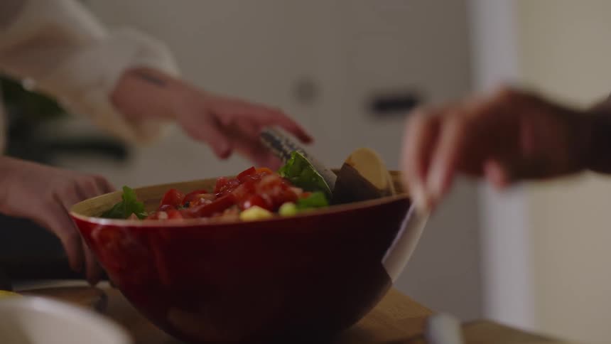 Women work together to prepare a salad while at home