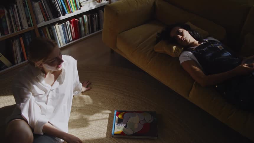 Friends relaxing in a room near a bookcase talk