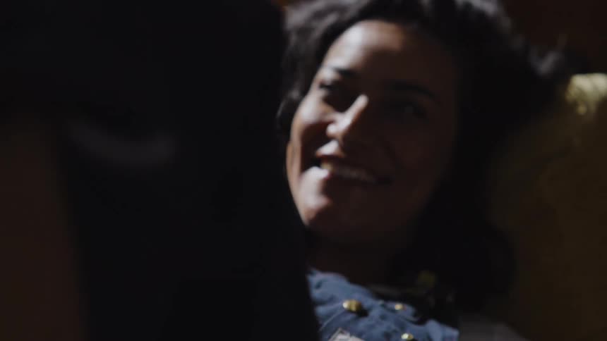 The face of a woman lying on a sofa and she is laughing while looking at someone who is in front of her