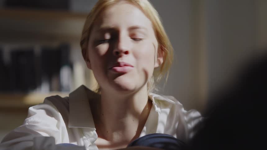 Portraits of a sitting blonde woman happily talking to another person