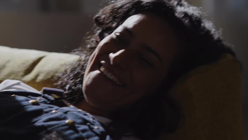 Portrait of a woman smiling while lying on a sofa