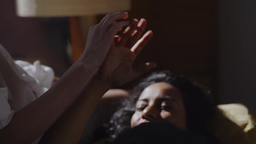 Women touch hands while one lies with her head in the others lap