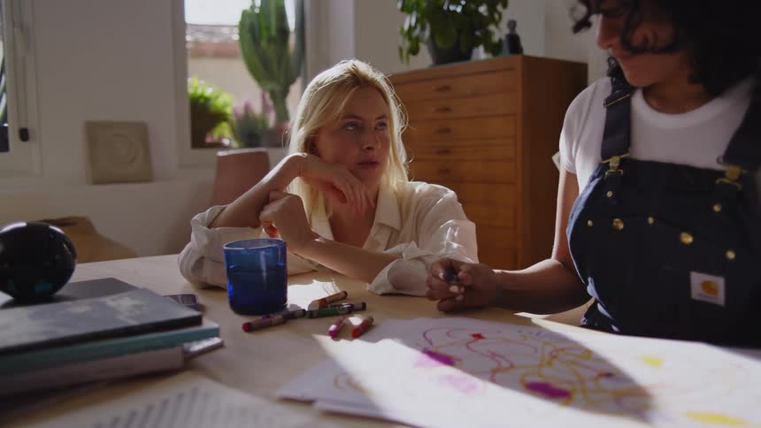 A woman is sketching as a friend talks with her