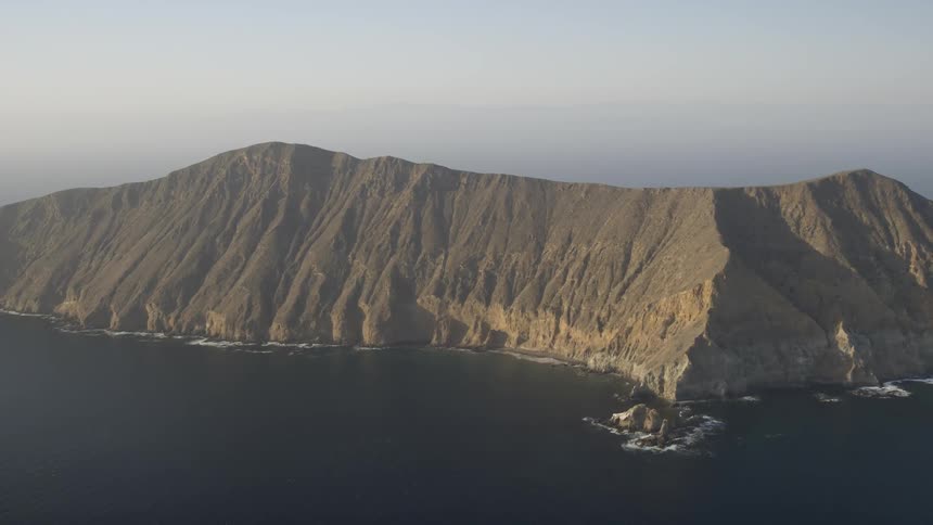 A mountain is surrounded by water at its base
