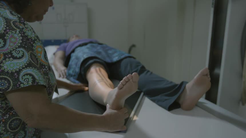 Technician adjusting a piece of equipment preparing to examine a patient's leg