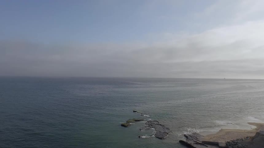 Aerial view of the edge of land leading out to the ocean on a cloudy day