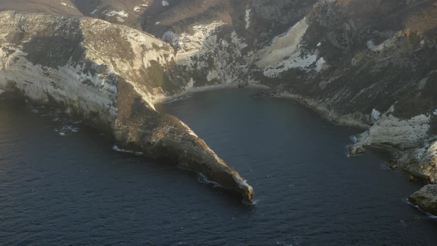 Water crashes against the shore of this mountain range below