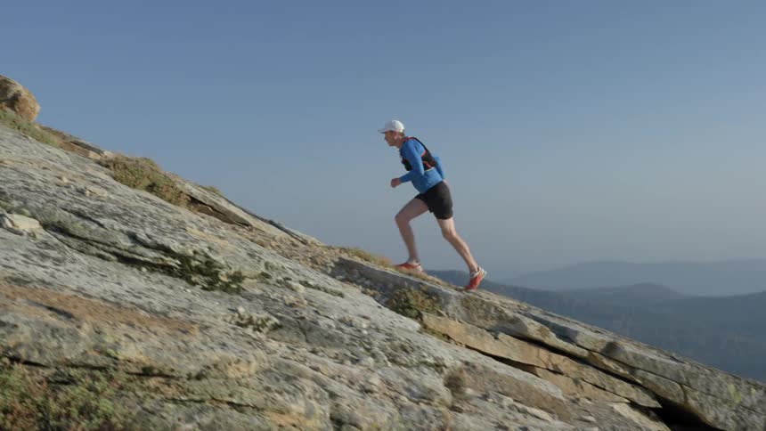 Man jogging up a rocky incline on a clear day