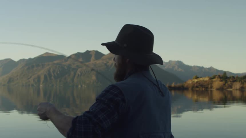 Man casts fishing line into a lake
