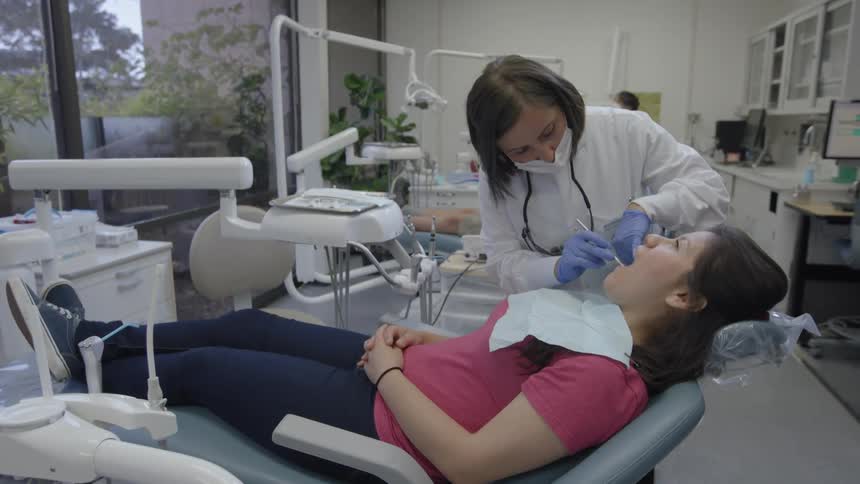 A woman is getting her teeth checked by a dentist