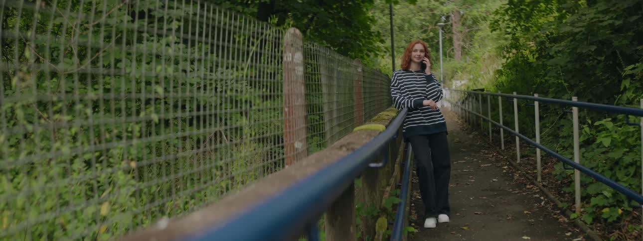 A clip of a lady standing by the barricade in a forest