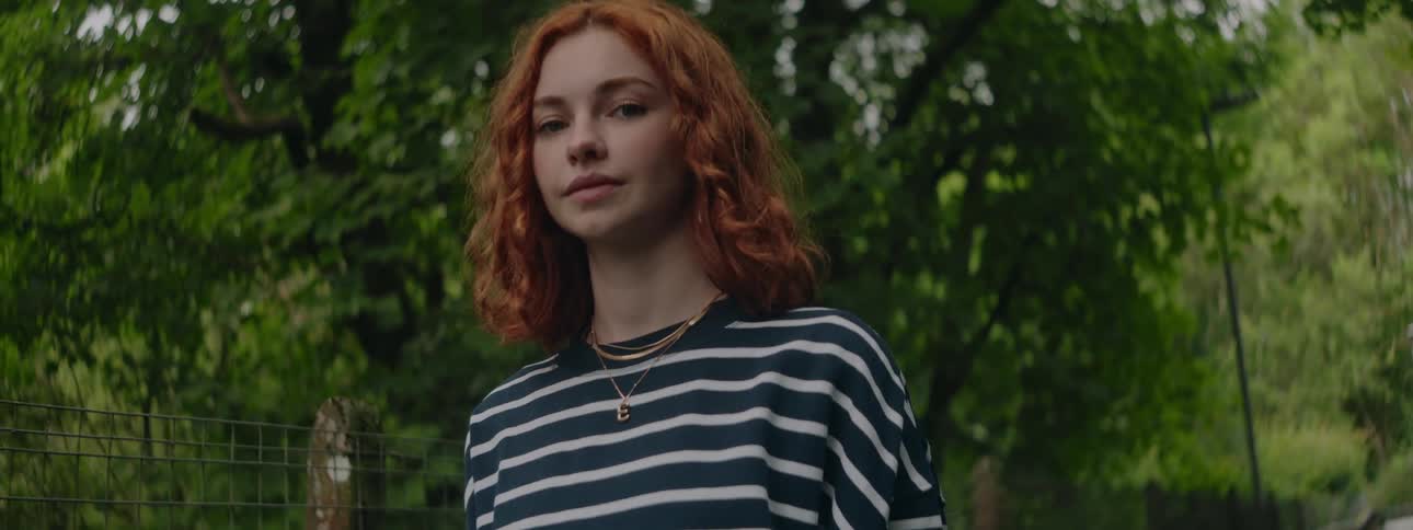 Portrait of a redhaired woman with curly hair in an area surrounded by trees