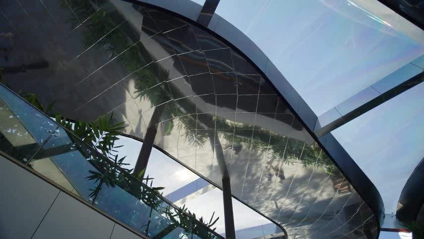 A modern architectural structure with a curved roof with reflecting surfaces and glass panels
