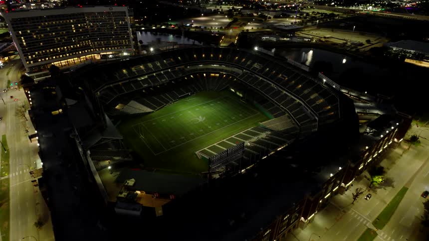 A large football stadium illuminated at night ready for a game under the lights