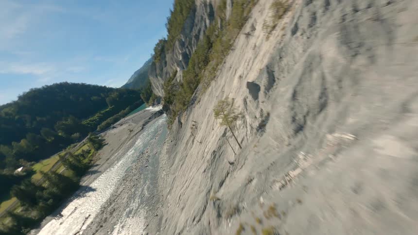Mountainous swiss landscape with a river running along a valley surrounded by sparse vegetation