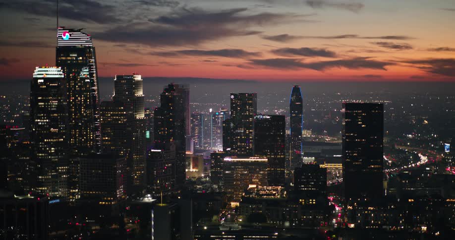 Aerial panorama of a metropolis with illuminated skyscrapers in the late afternoon with a reddish sky