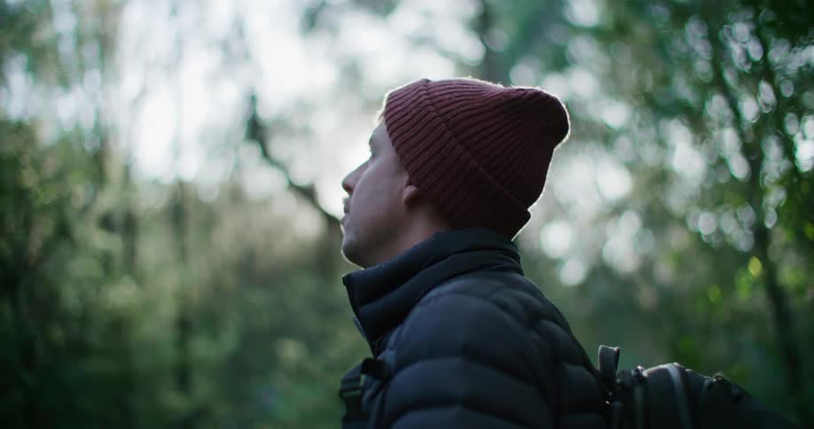 Man with a red cap standing watching trees in nature