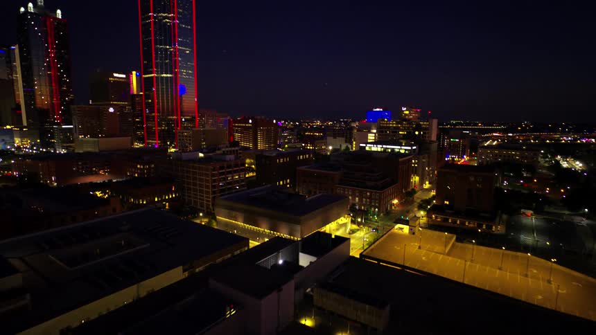Aerial view of a skyscraper with red lights highlighted by a metropolis illuminated at night