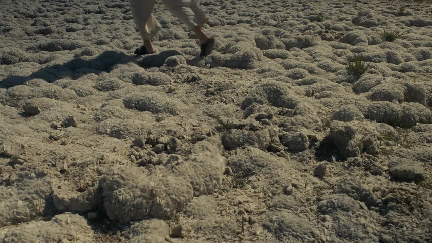 Legs of a person walking through an area with rocks and sand
