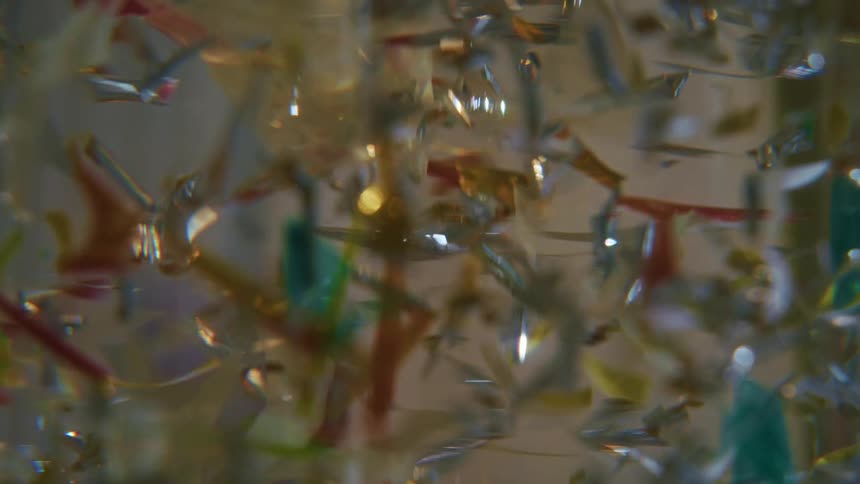A close up of colorful shiny objects floating in a clear liquid reflecting light