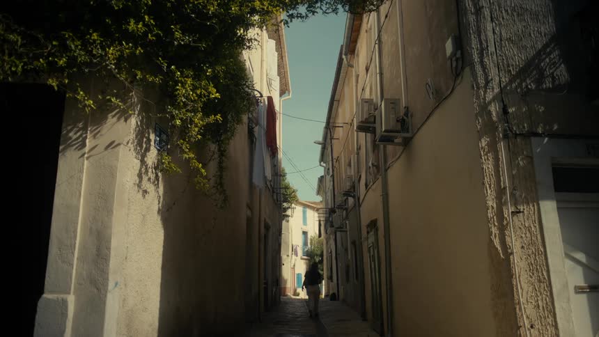 Woman walking down an alley between old and classic residential buildings during daytime